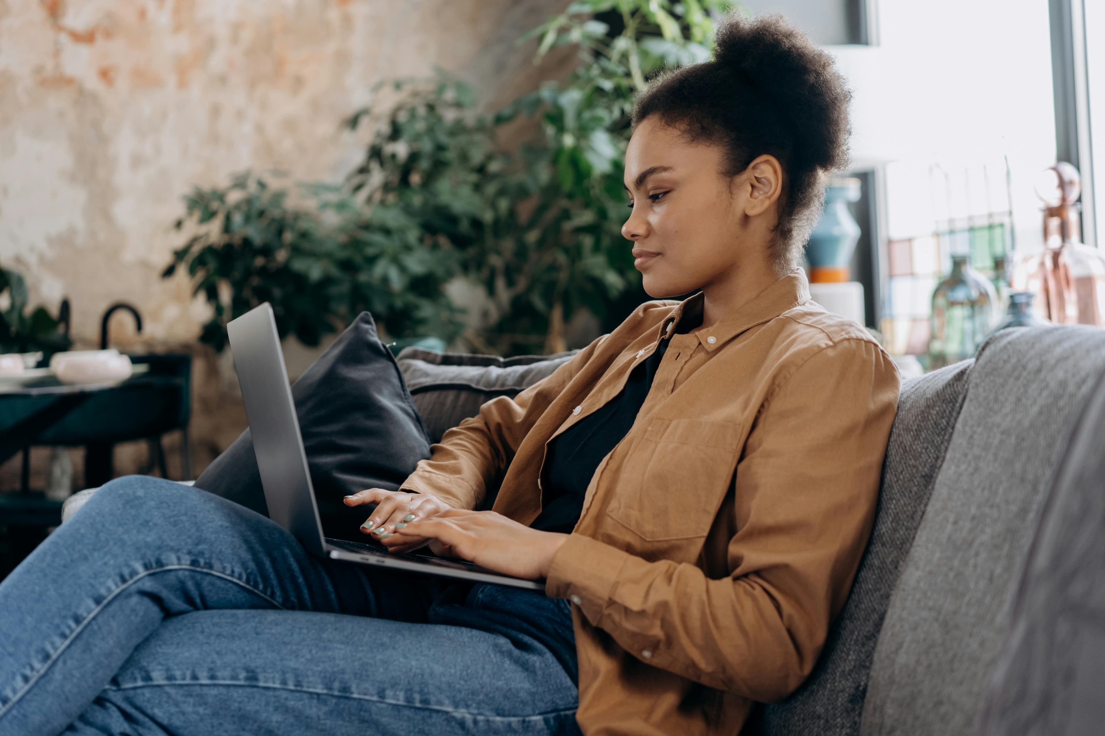 Person sitting on couch, using a laptop computer.