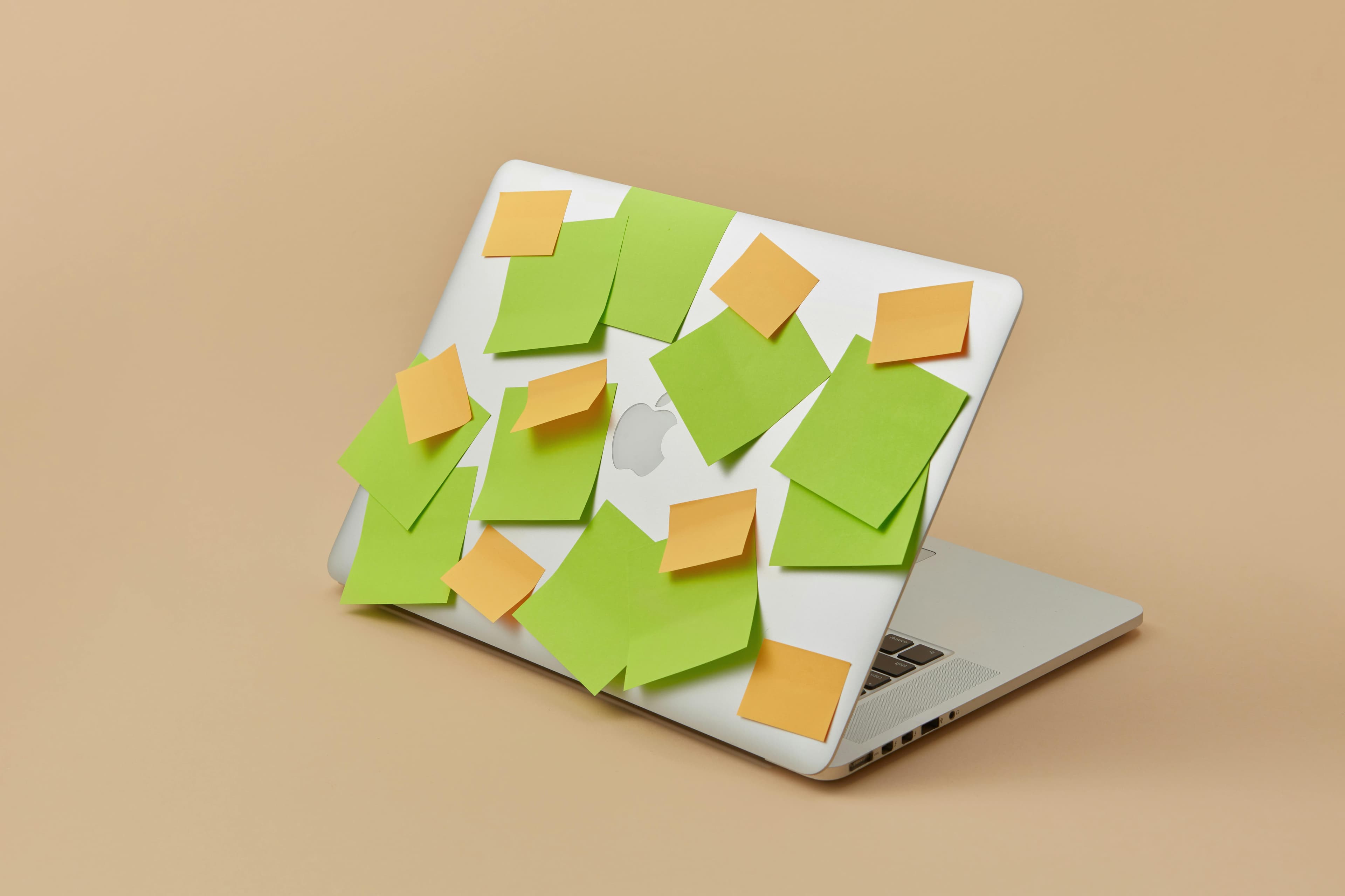 An Apple Laptop with Sticky Notes Stuck on Top Panel